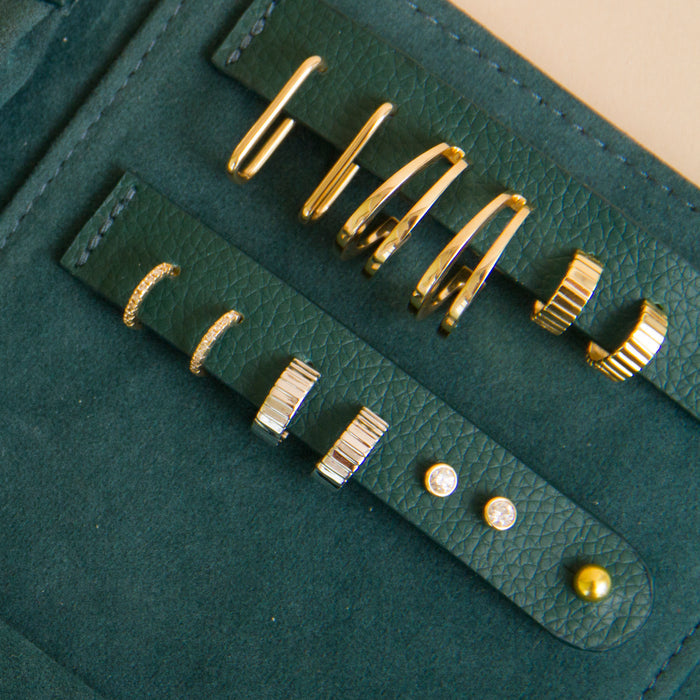 Flatlay Model. A close-up flatlay shot of various earrings in a green travel case.