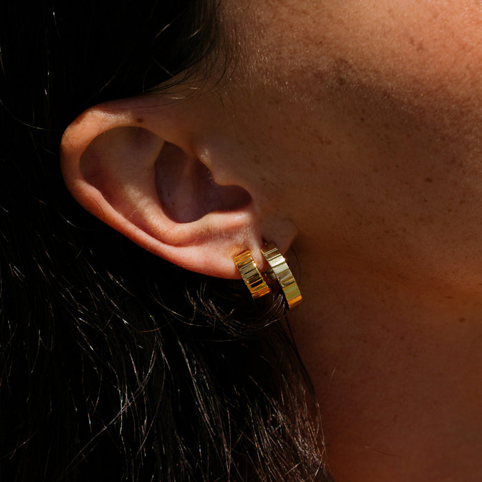 Lifestyle Model. A close-up side profile lifestyle shot of a woman wearing two gold hoop earrings