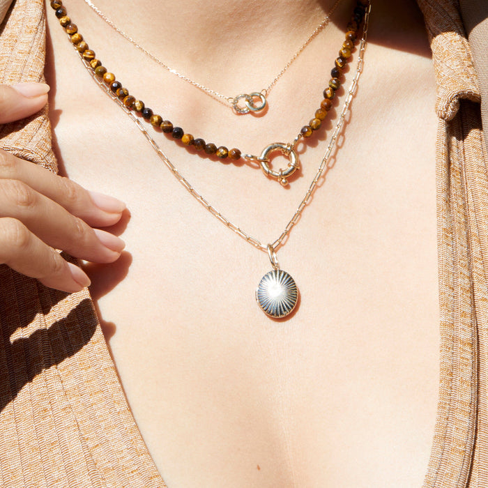 Model. Close-up of a person wearing two necklaces with a focus on the pendant details.