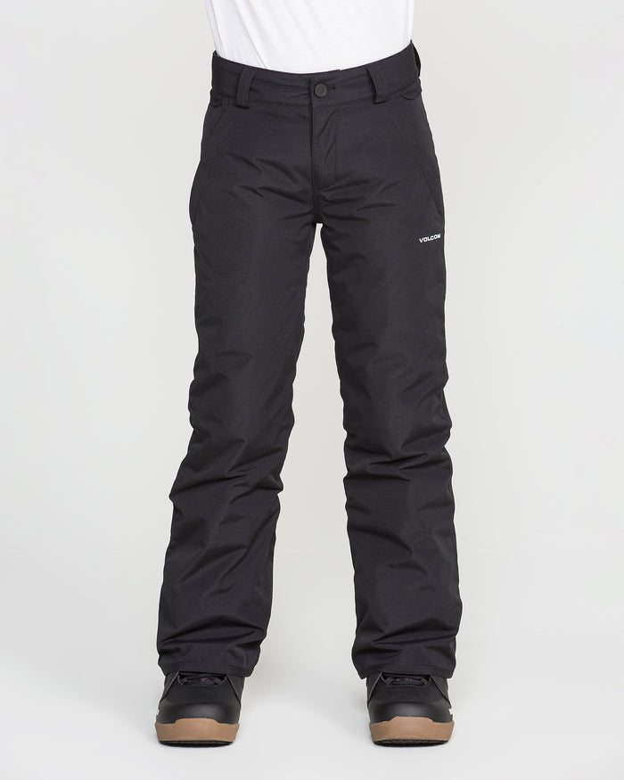 A person wearing black Volcom Kids’ Youth Freakin Chino Insulated Pants with an adjustable waist and black boots stands against a plain white background. The waterproof, breathable snow pants feature a small white Volcom logo on the left thigh. The person’s upper body is not visible.