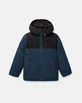 The Volcom Kids’ Youth Stone.91 Insulated Jacket is shown on a white background, featuring a blue body with a black, helmet-ready hood and shoulder section, a front zipper, and two zippered side pockets. It offers 10K/10K V-Science protection and recycled insulation.