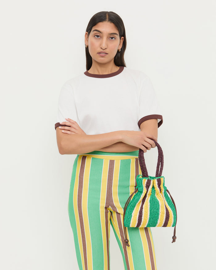 Kylie Green/Yellow Raffia Drawstring Pouch, Harly Tee in white cotton with brown accents, and Pasha Trouser in green/yellow striped cotton-linen.
