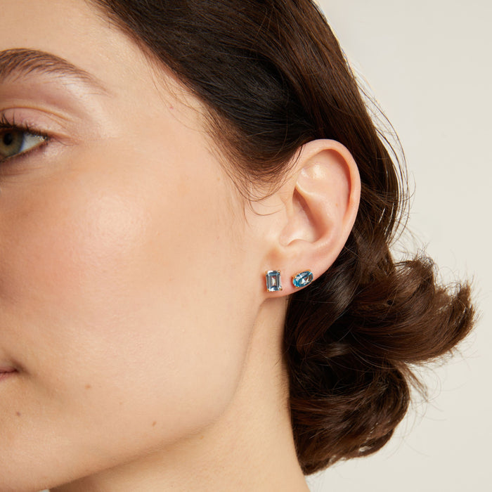 Woman wearing two blue stud earrings. Model