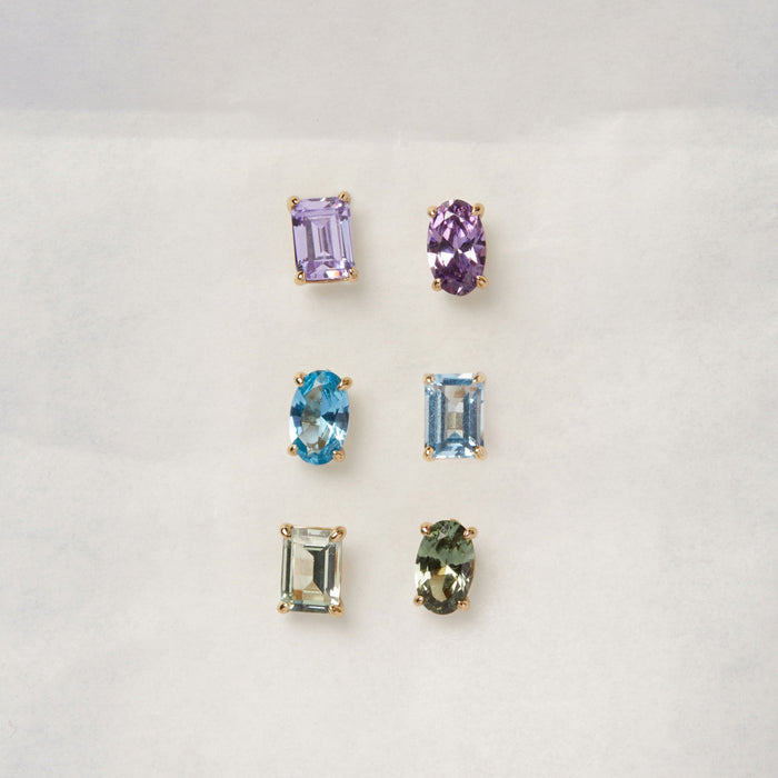 Model. Three sets of gemstone earrings on a light gray background