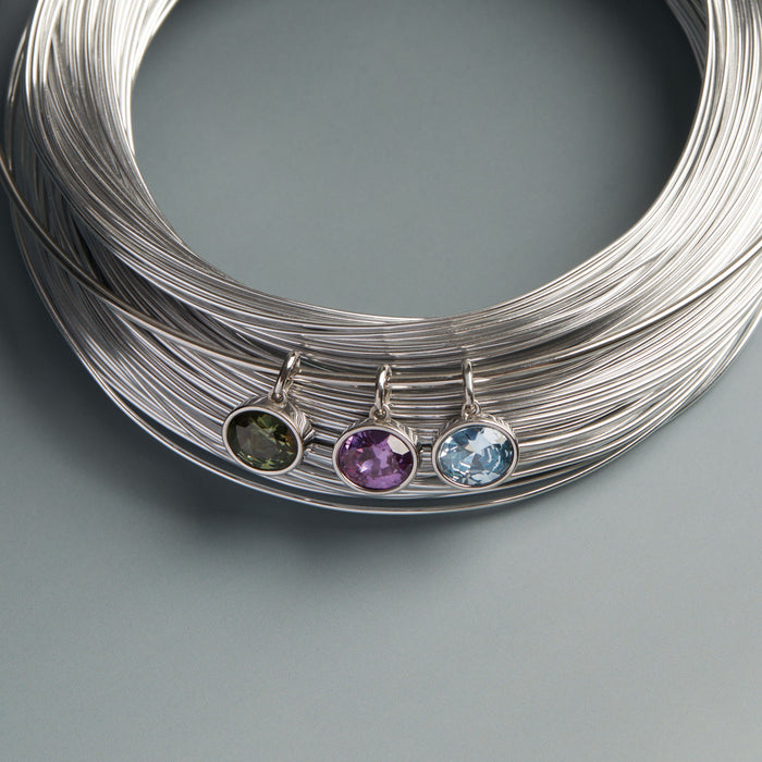 Model. Three gemstone pendants on silver wires against a gray background