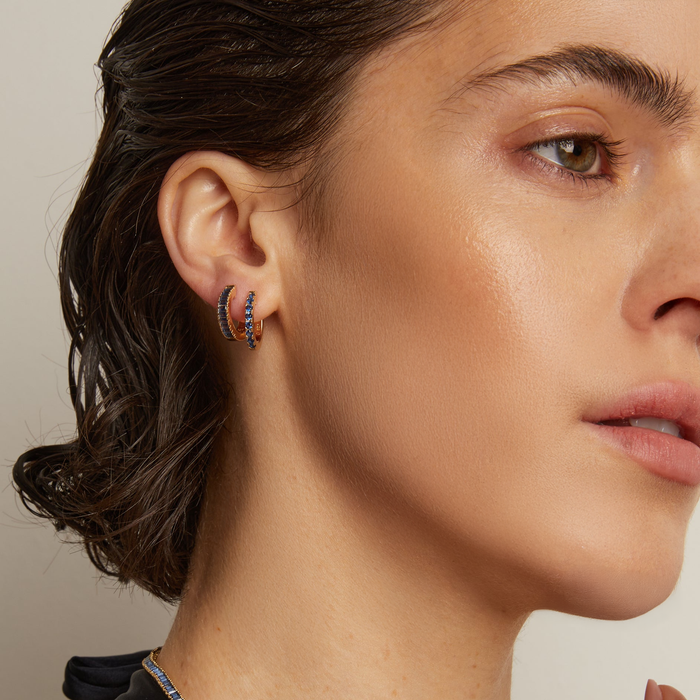 Model.  Close up of woman wearing two blue stone hoop earrings