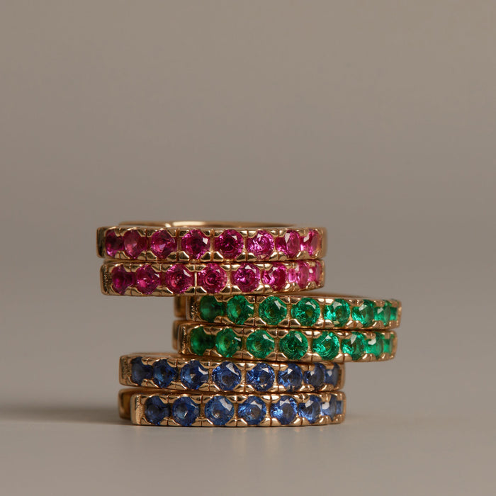 Model. Stack of gold rings with gemstones on a beige background