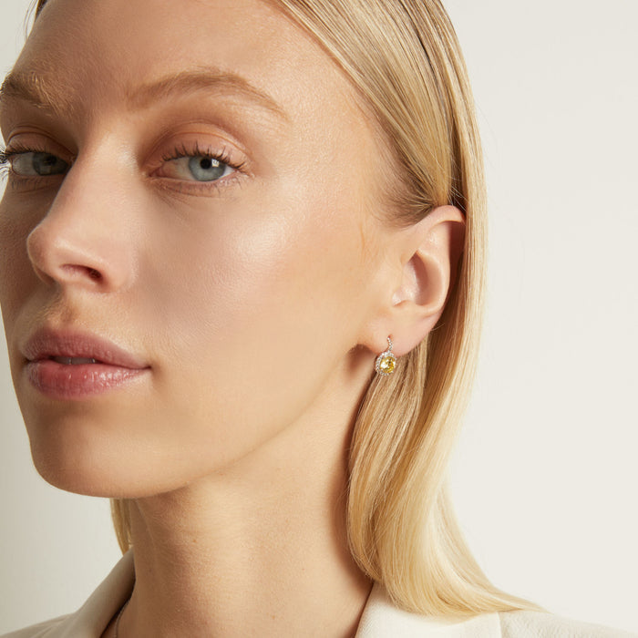 Model. Close-up of a woman wearing gold earrings with a neutral background