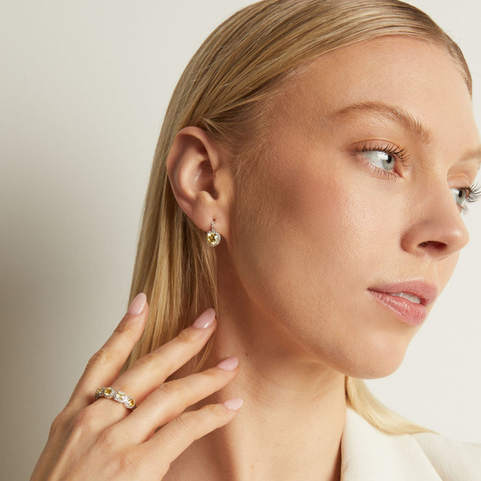Model. Woman wearing gold earrings and a ring, with a neutral background