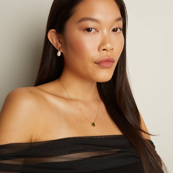 Model. Woman wearing a black off-shoulder top with a plain background