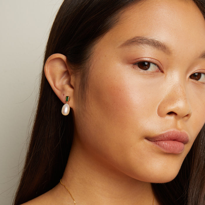 Model. Close-up of a woman wearing pearl earrings with a neutral background