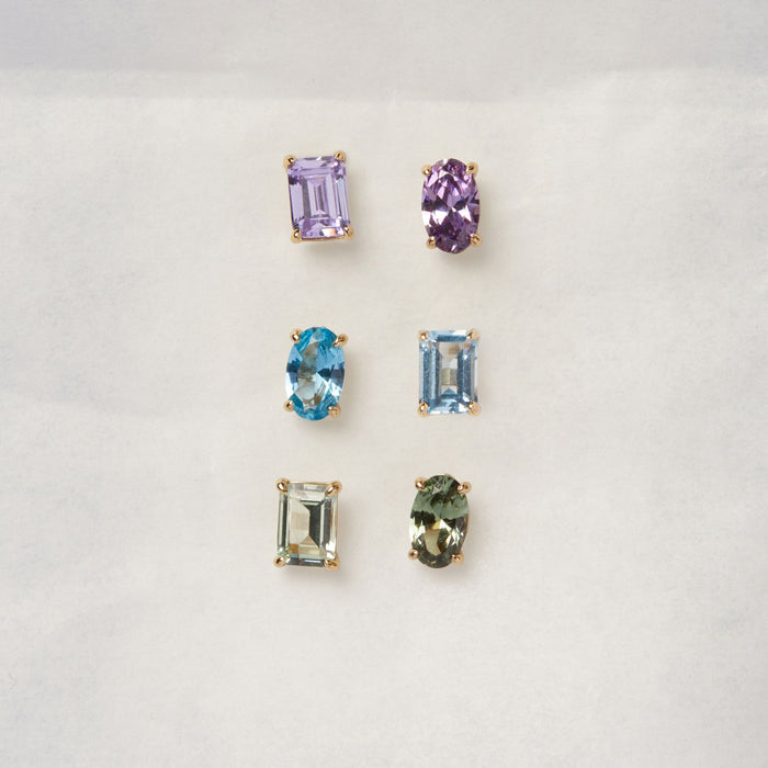 Model. Three sets of gemstone earrings on a light gray background