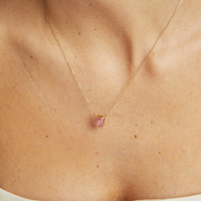 Model. Gold necklace with a pink gemstone pendant on a person's neck