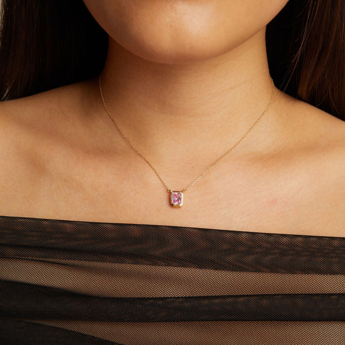 Model. Necklace with a pink gemstone pendant worn by a person