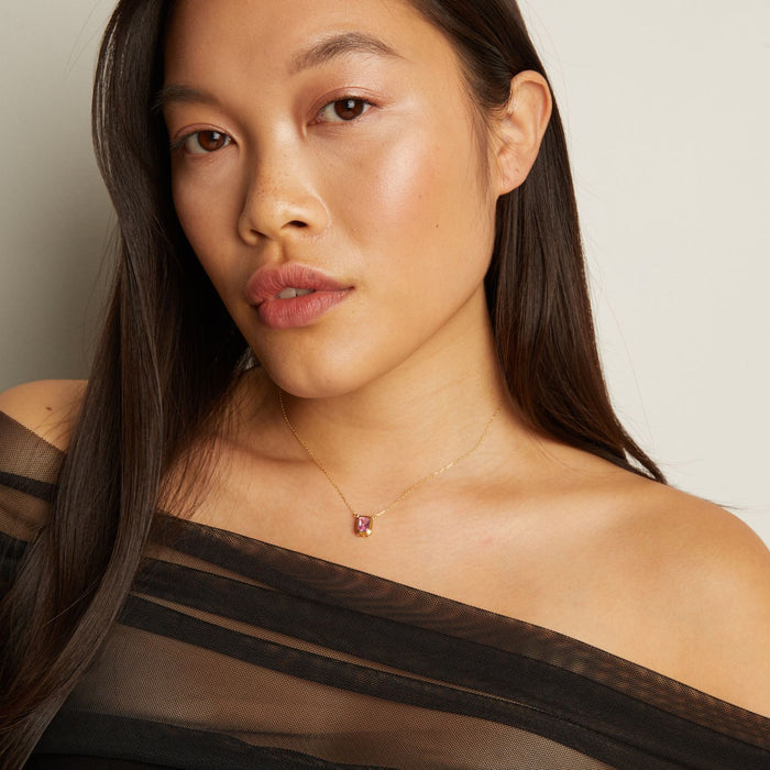 Model. Woman wearing a necklace with a small pendant against a neutral background