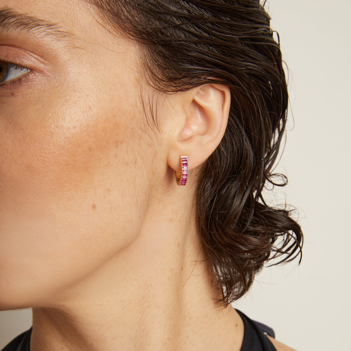 Model. Close-up of a person wearing pink hoop earrings with a neutral background
