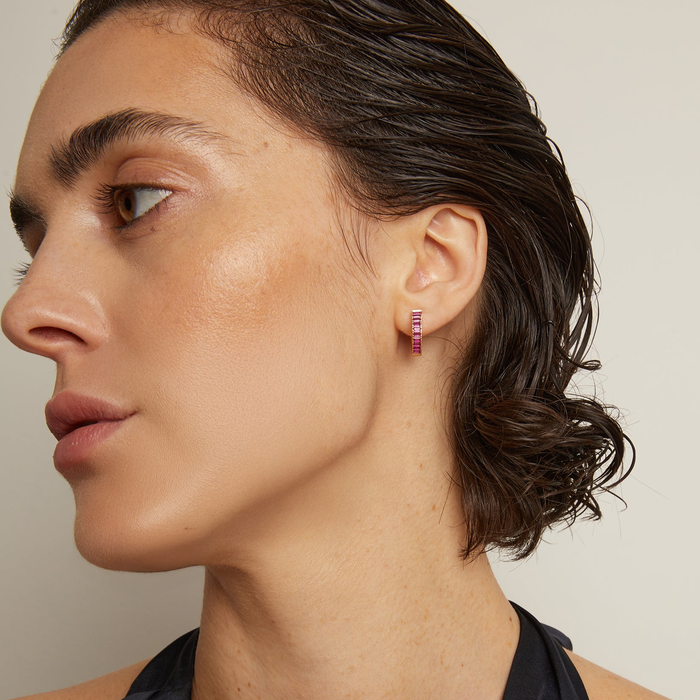 Model. Close-up of a woman wearing pink hoop earrings with a neutral background