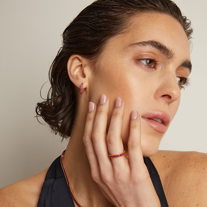 Model. Woman wearing earrings and a ring with a neutral background
