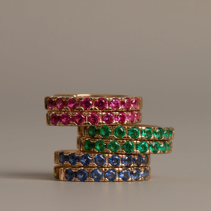 Model. Stack of gold rings with gemstones on a beige background