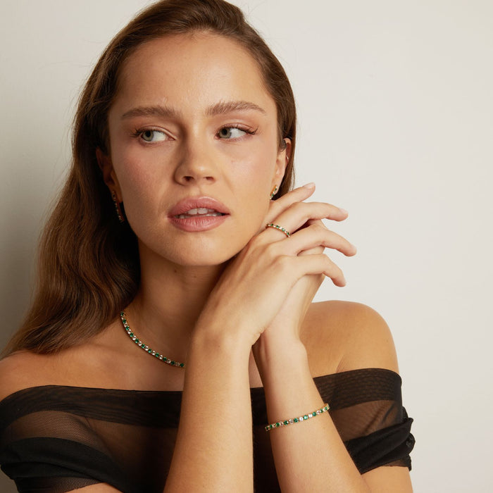 Model. Woman wearing a black off-shoulder top with jewelry on a neutral background