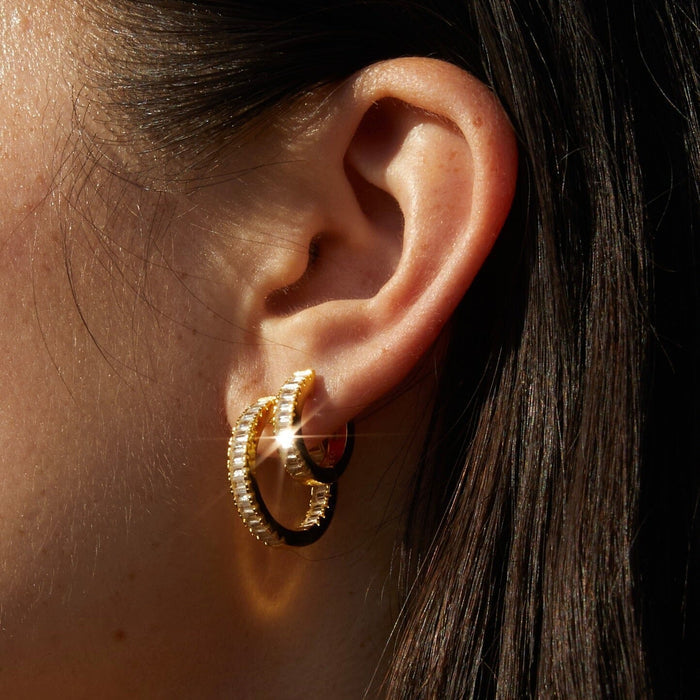 Model.  close up of woman wearing two gold hoop earrings