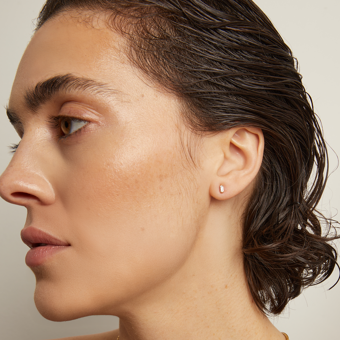 Model. Woman wearing a gold necklace against a neutral background