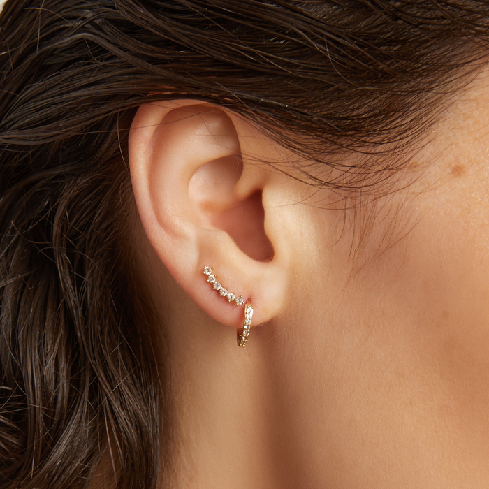 Close-up of an ear wearing a diamond hoop and stud earring.