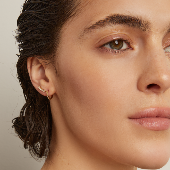 Close-up of a woman wearing stud earrings with a neutral background