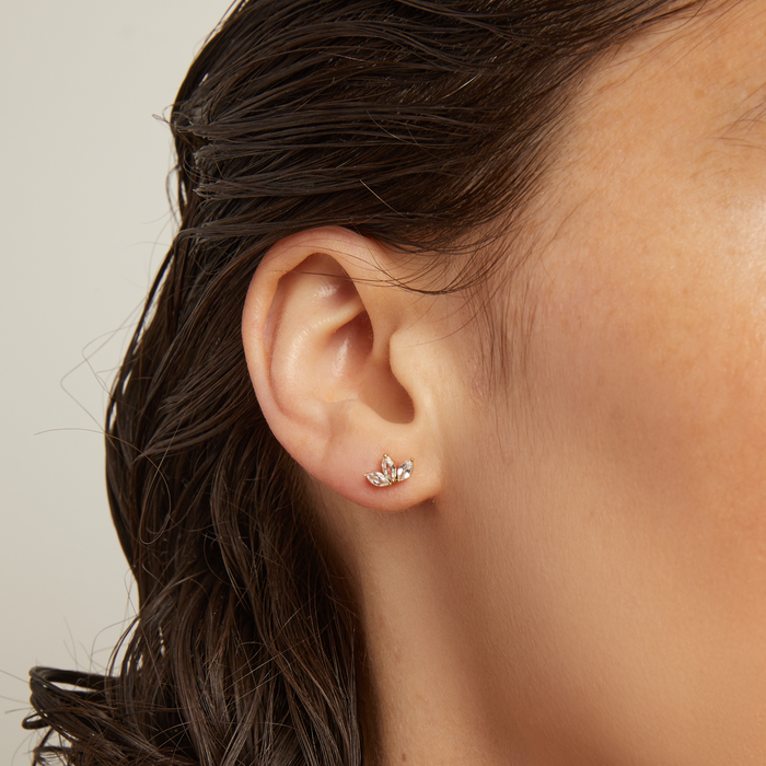 Model. Close-up of an ear wearing a small earring with a neutral background