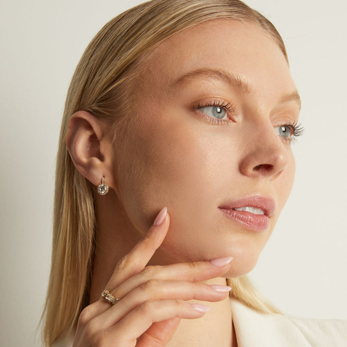 Model. Close-up of a woman wearing earrings and a ring with a neutral background