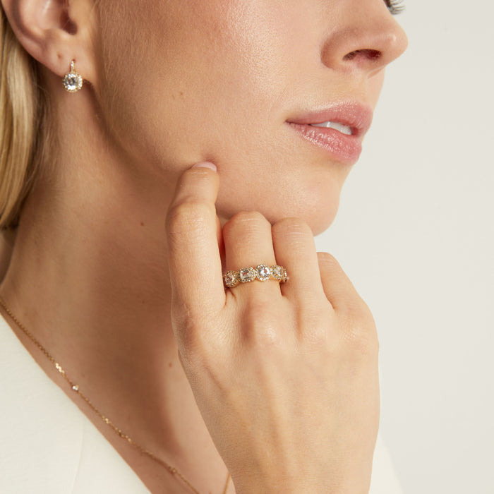 Model. Close-up of a woman's face wearing a diamond ring and earrings on a neutral background