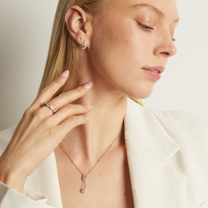Model. Woman wearing a necklace, earrings, and ring with a neutral background
