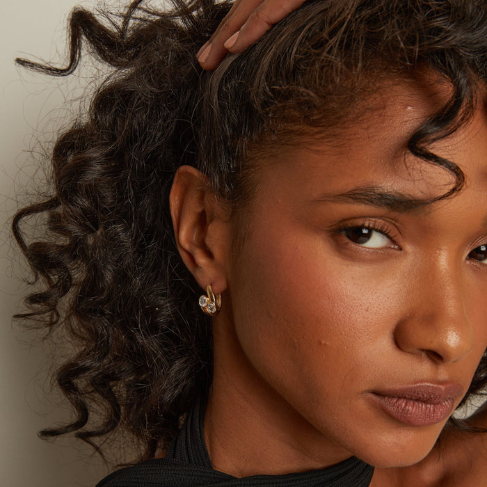 Model. Close-up of a woman with curly hair and earrings against a neutral background