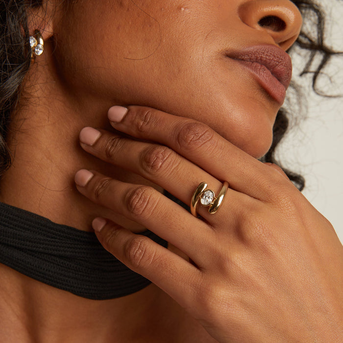 Model. Close-up of a person wearing a gold ring with a diamond on their hand.