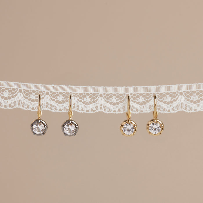 Model Gold earrings with clear stones on a beige background with lace trim