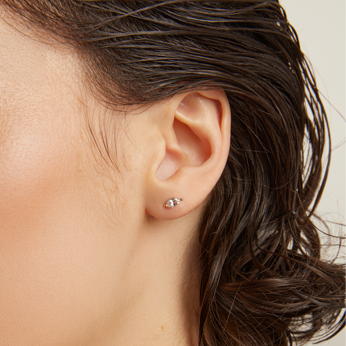 Model. Close-up of a person wearing an earring with a neutral background