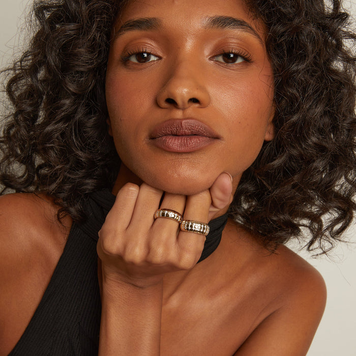 Model. Woman with curly hair wearing a black top against a neutral background