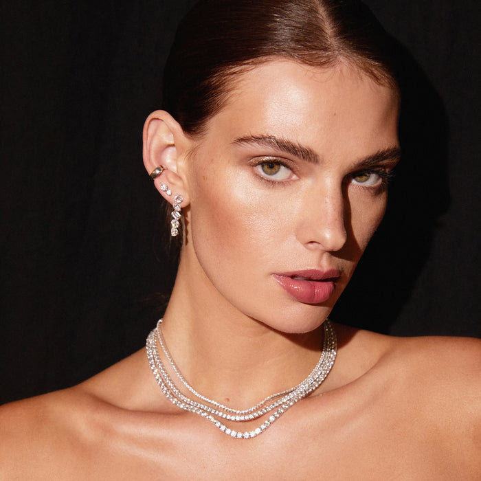 Model. Close up of woman wearing various earrings and stacked tennis necklaces