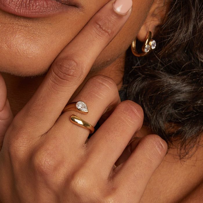 Model. Close-up of a person's hand with gold rings and a diamond earring.