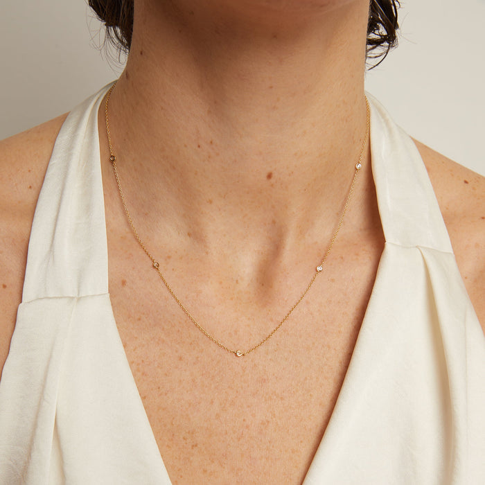 Model. Necklace with small heart pendants worn by a person in a white top against a neutral background