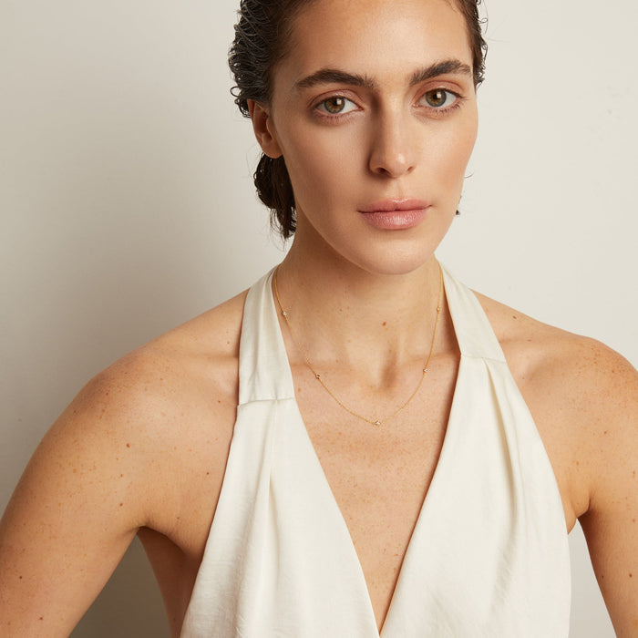 Model. Woman wearing a white halter neck top against a plain background