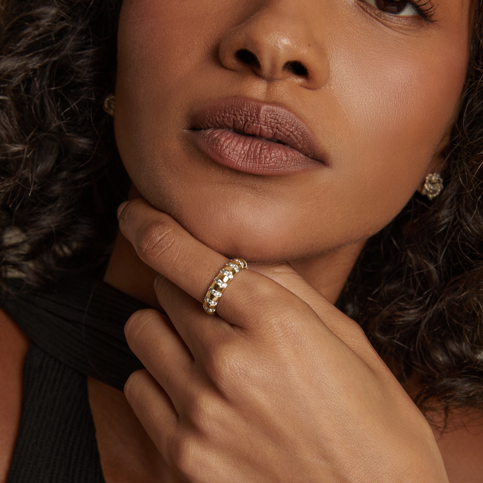 Model. Close-up of a woman's hand with a gold ring, wearing a black top.