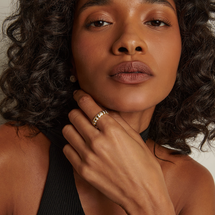Model. Woman with curly hair wearing a gold ring, close-up portrait.