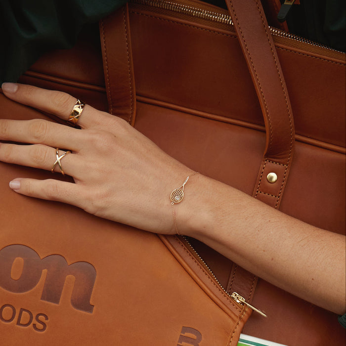 Model. Hand with gold rings and bracelet on a brown leather bag
