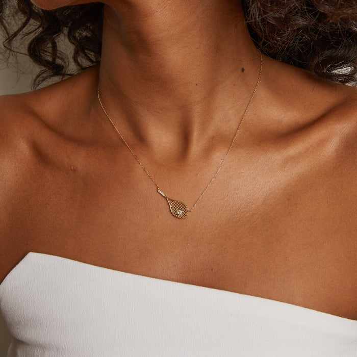 Model. Necklace with a heart-shaped pendant on a person wearing a white top.