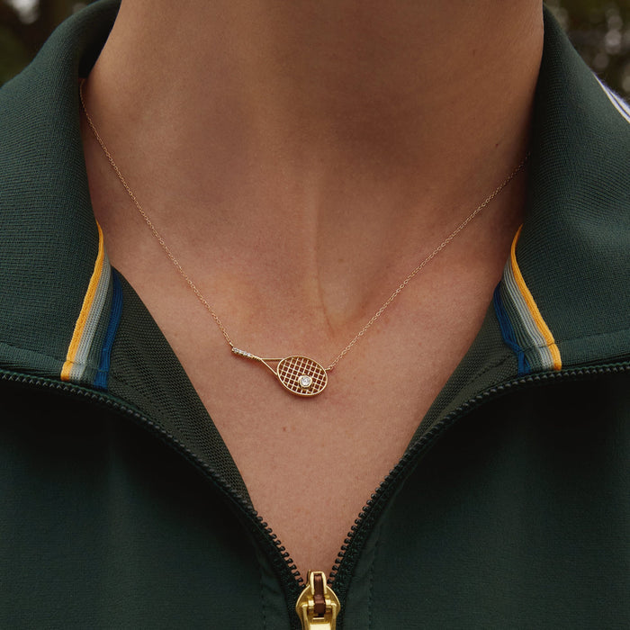 Model. Close-up of a person wearing a green jacket with a gold necklace featuring a heart-shaped pendant.