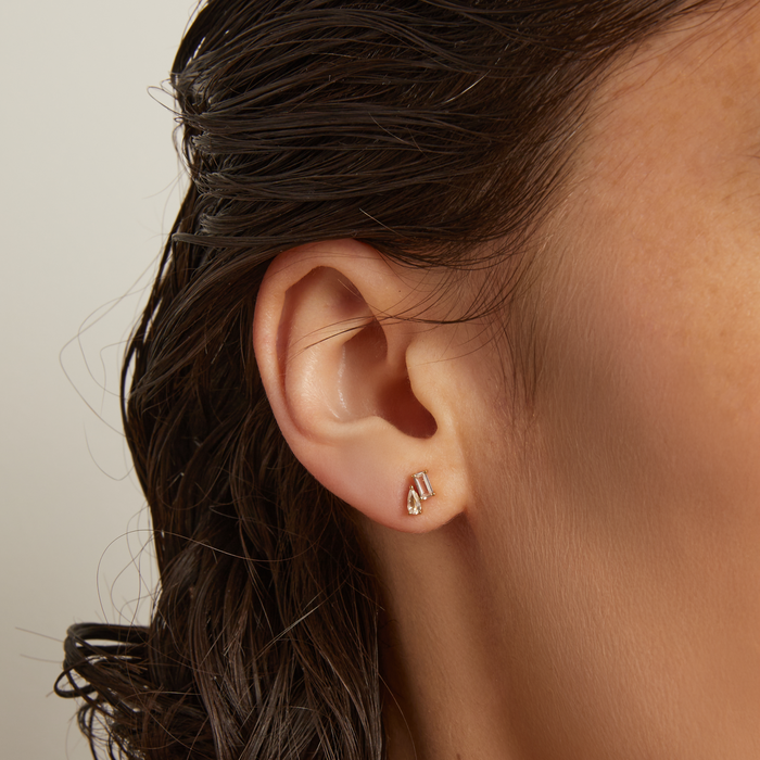 Model. Close-up of an ear wearing a small earring with a neutral background
