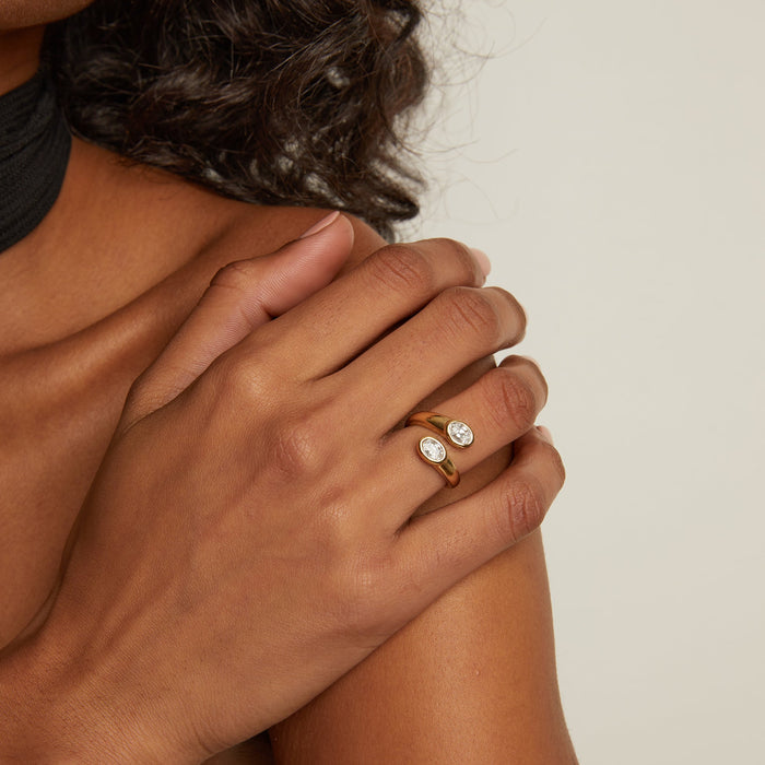 Model. Close-up of a hand wearing a gold ring with a diamond on a neutral background