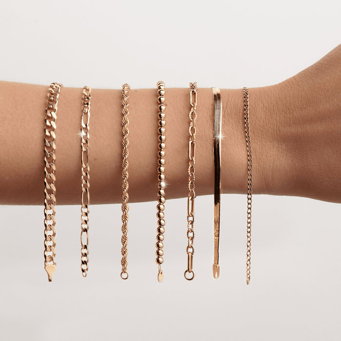 Lifestyle Model. Close up of woman's arm with 7 gold chain bracelets hanging on it