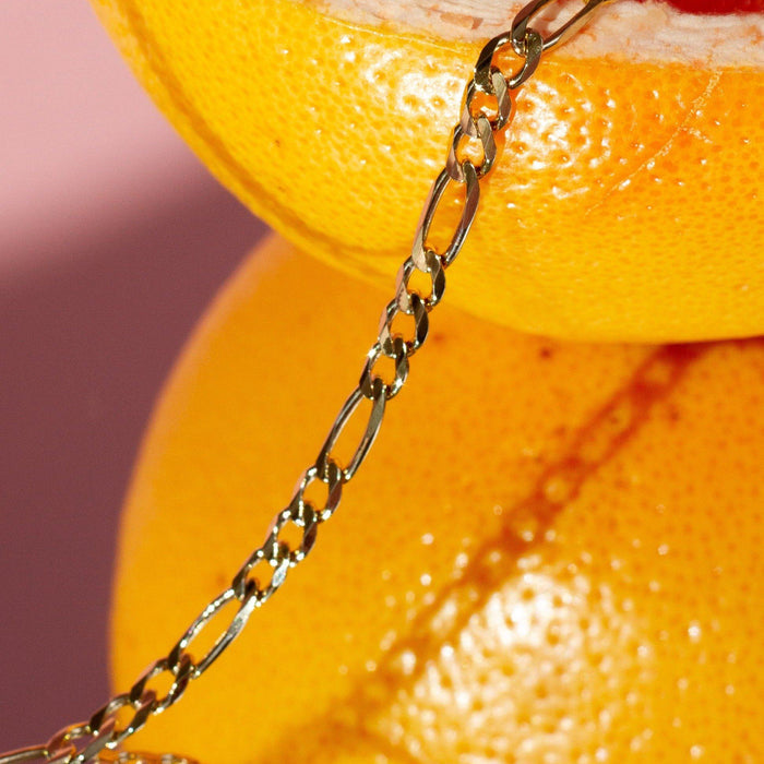 Flatlay Model. Close up of gold chain bracelet resting on lemon